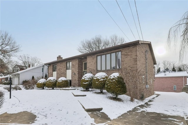 view of front facade featuring brick siding, a chimney, and an attached garage