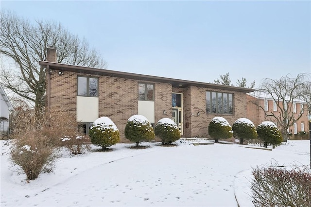 bi-level home featuring a chimney and brick siding