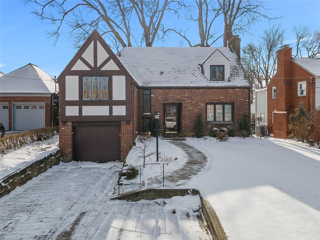 english style home featuring central air condition unit, a garage, brick siding, stucco siding, and a chimney