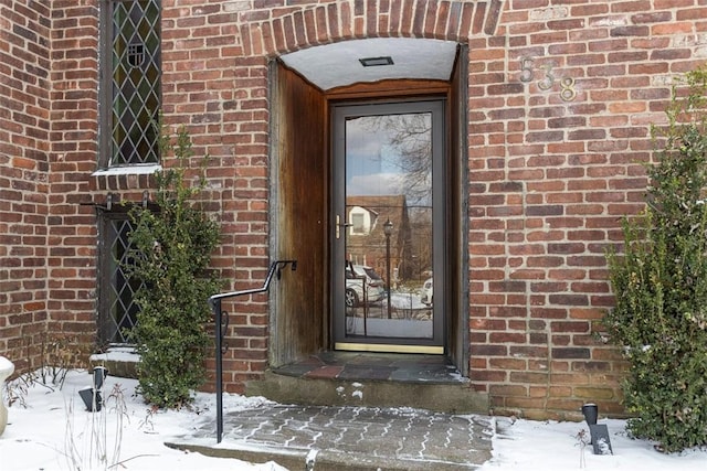 snow covered property entrance with brick siding