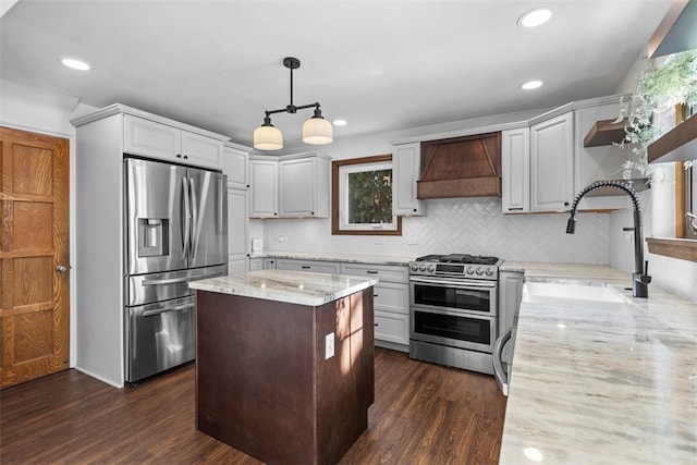 kitchen with light stone counters, decorative light fixtures, custom exhaust hood, open shelves, and appliances with stainless steel finishes