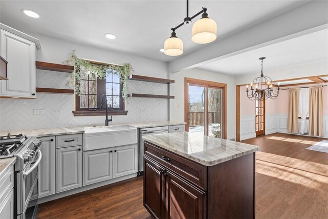 kitchen featuring open shelves, light stone counters, a sink, and stainless steel appliances