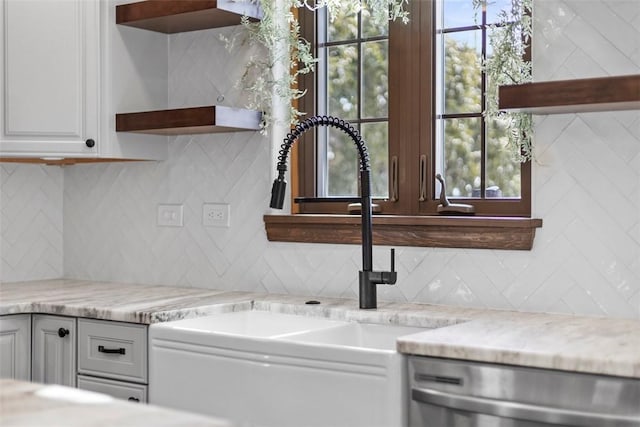 kitchen featuring light stone counters, white cabinets, a sink, and open shelves