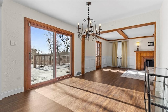 doorway to outside featuring a fireplace, wood finished floors, visible vents, and a notable chandelier