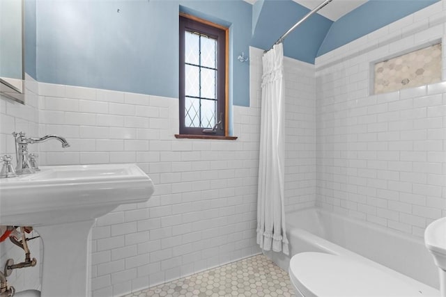 bathroom featuring shower / tub combo, wainscoting, toilet, tile patterned floors, and tile walls