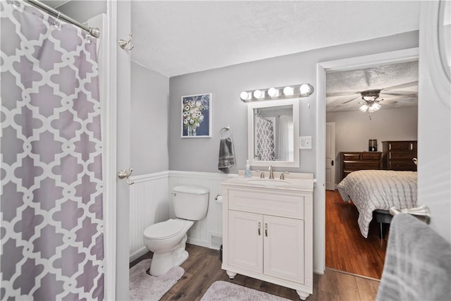 bathroom featuring a wainscoted wall, wood finished floors, vanity, a textured ceiling, and ensuite bath