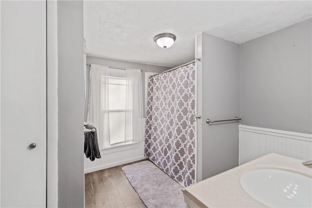 full bath with a wainscoted wall, a textured ceiling, wood finished floors, and vanity