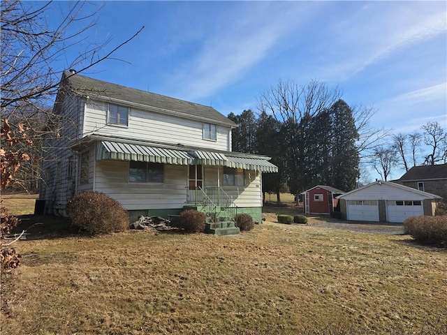 view of front of house featuring a detached garage, a storage unit, a front lawn, and an outbuilding