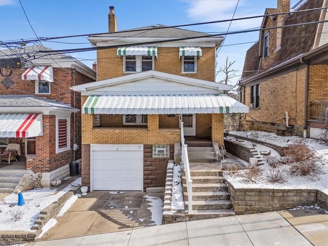 american foursquare style home featuring concrete driveway, brick siding, a chimney, and an attached garage