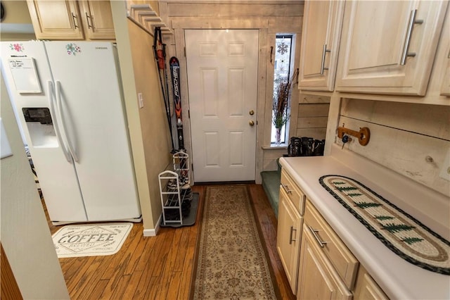 kitchen featuring light wood-style floors, white refrigerator with ice dispenser, light countertops, and light brown cabinetry