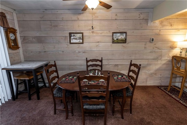 carpeted dining area featuring ceiling fan and wooden walls