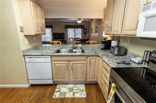 kitchen featuring light stone counters, white appliances, a sink, light brown cabinetry, and dark wood finished floors