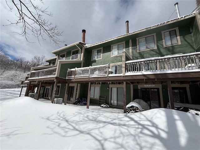 snow covered back of property featuring a balcony