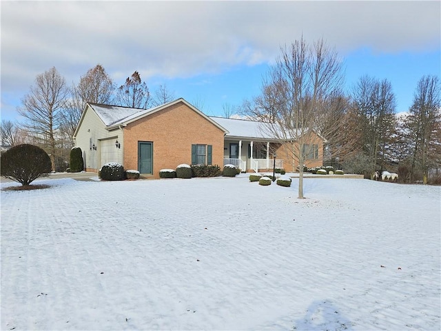 exterior space with covered porch, brick siding, and an attached garage