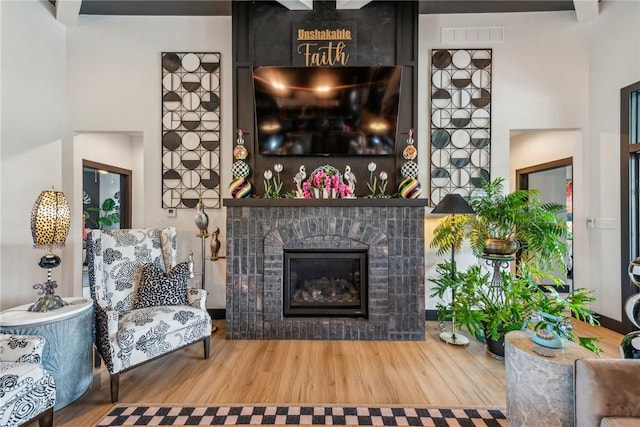 living area with wood finished floors, a glass covered fireplace, and visible vents