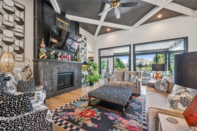 living area with a fireplace, coffered ceiling, wood finished floors, and a healthy amount of sunlight