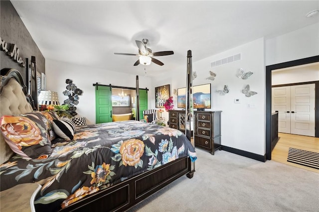 bedroom featuring a barn door, light colored carpet, a ceiling fan, baseboards, and visible vents