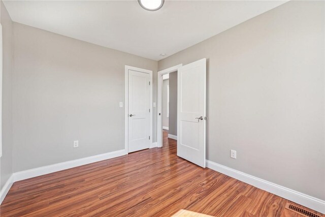 spare room with baseboards, visible vents, and wood finished floors