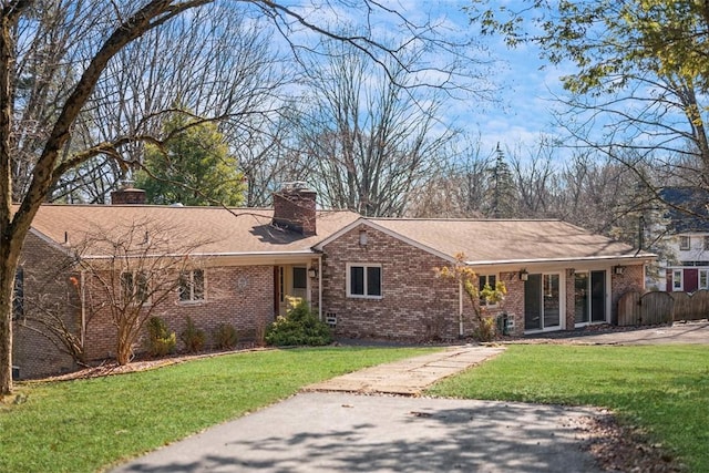 ranch-style home featuring a chimney, fence, a front lawn, and brick siding