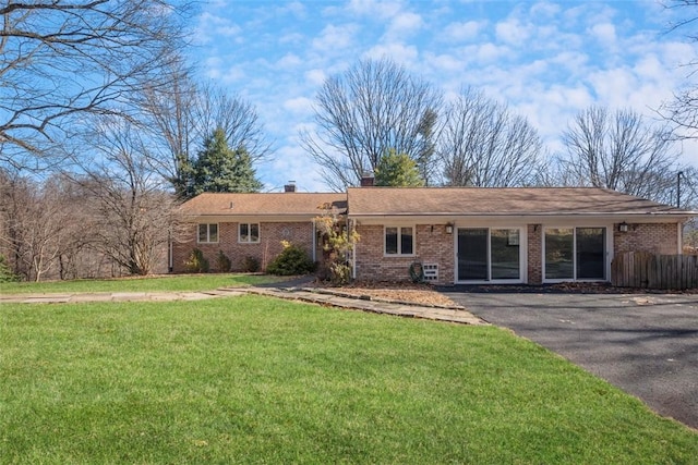 single story home with brick siding, fence, a chimney, and a front lawn