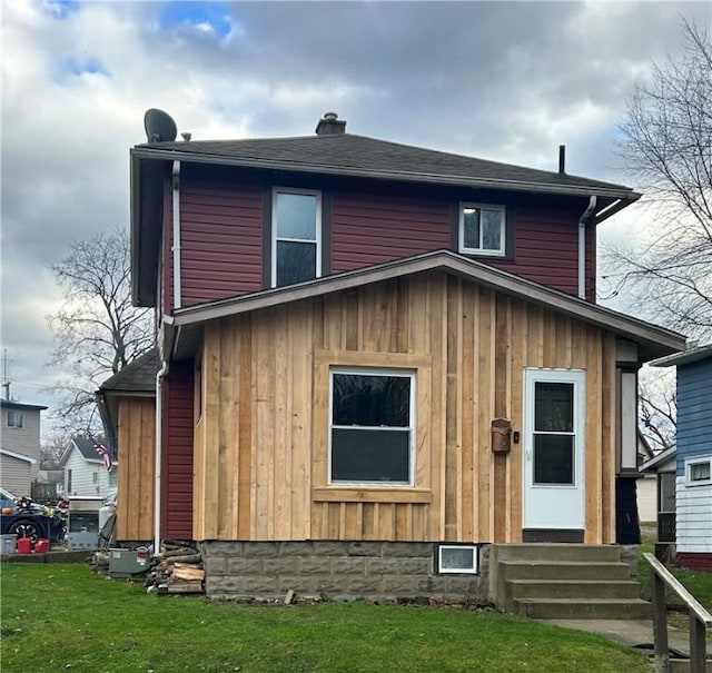 view of front of property with entry steps, roof with shingles, and a front yard