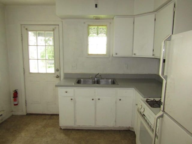 kitchen with a sink, white appliances, and white cabinets