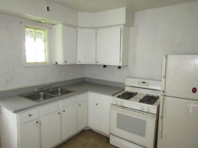 kitchen with white appliances, a sink, and white cabinetry