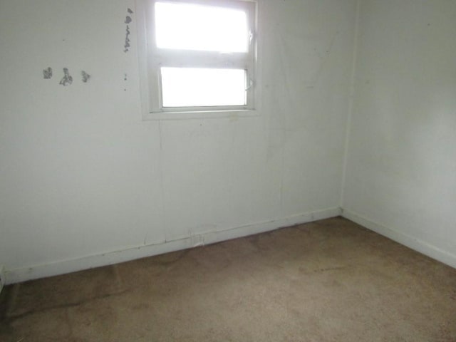 unfurnished room with light carpet and baseboards