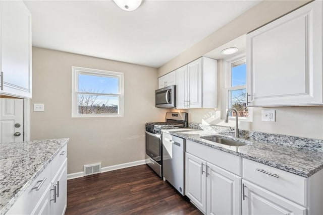 kitchen featuring stainless steel appliances, white cabinets, a sink, and visible vents