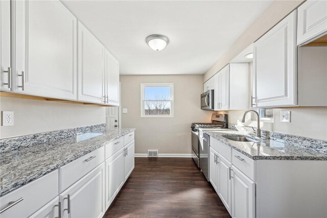 kitchen featuring appliances with stainless steel finishes, white cabinets, a sink, and visible vents