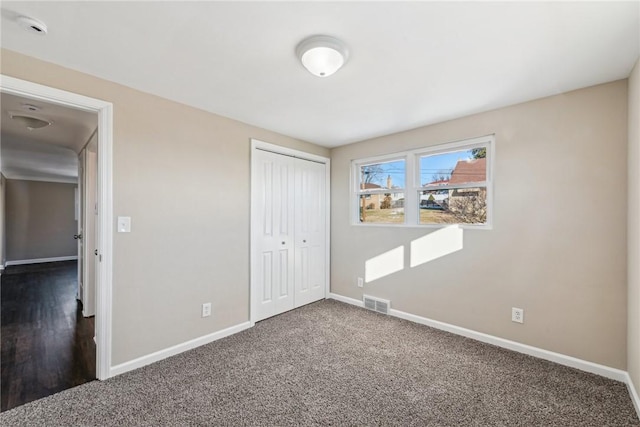 unfurnished bedroom with a closet, carpet flooring, visible vents, and baseboards