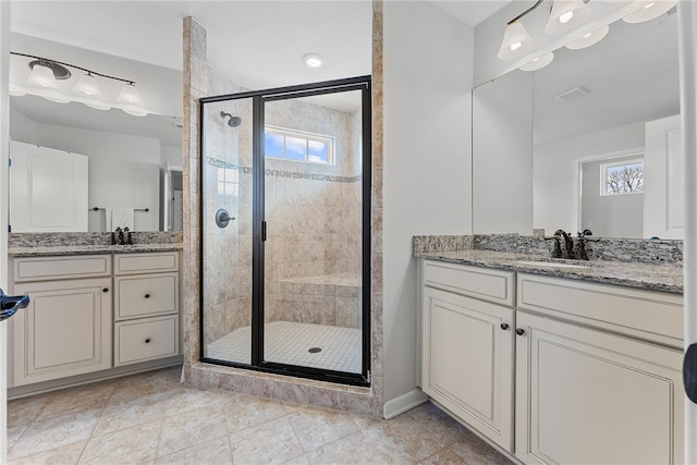 full bath with a shower stall, two vanities, and a sink