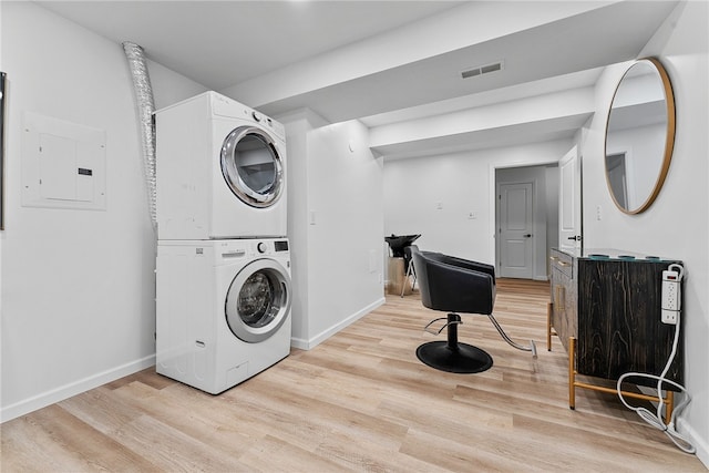 clothes washing area with stacked washer and dryer, electric panel, light wood-style floors, and visible vents