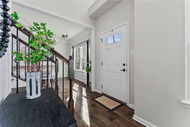 foyer featuring stairs, dark wood-type flooring, baseboards, and crown molding