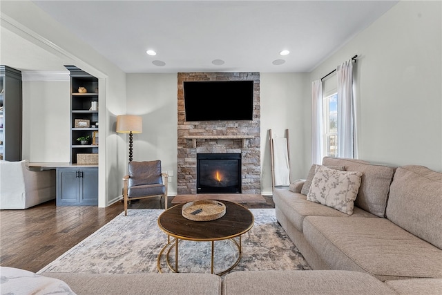 living area with dark wood-style floors, recessed lighting, and a stone fireplace