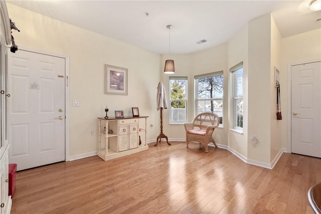 living area featuring light wood-type flooring, visible vents, and baseboards