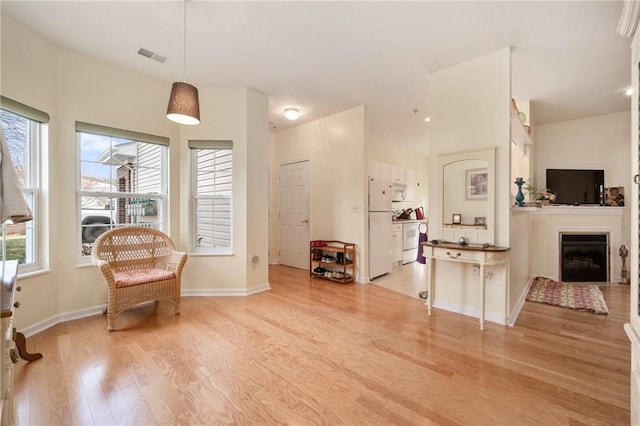 sitting room with light wood-style floors, visible vents, a fireplace, and baseboards