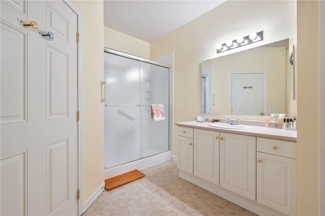 bathroom featuring tile patterned floors, a shower stall, baseboards, and vanity