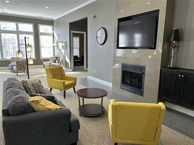 living room with a tile fireplace, crown molding, a textured ceiling, and baseboards