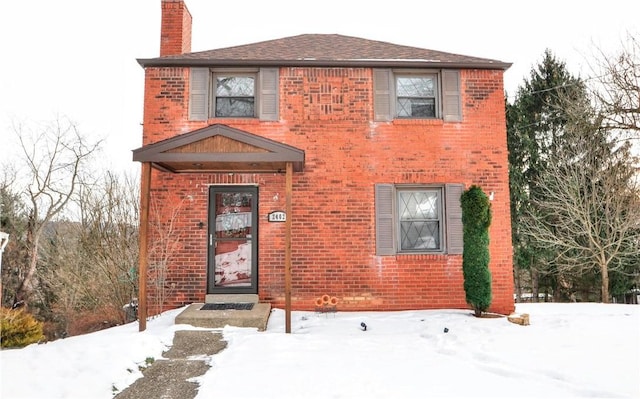 view of front facade featuring brick siding and a chimney