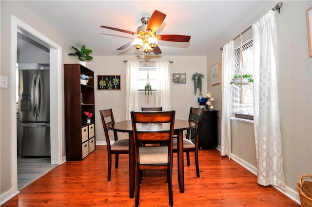 dining room with wood finished floors, a ceiling fan, and baseboards