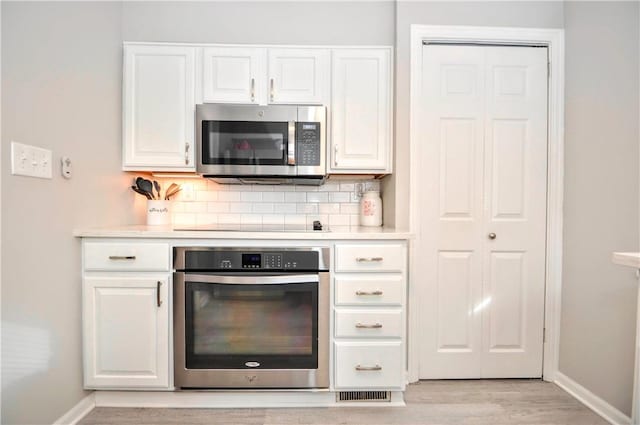 kitchen featuring stainless steel appliances, white cabinets, and light countertops