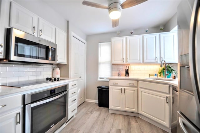 kitchen with light countertops, appliances with stainless steel finishes, a sink, and white cabinets