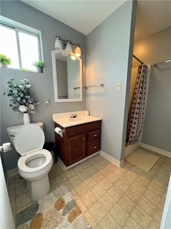 bathroom featuring a stall shower, vanity, and baseboards