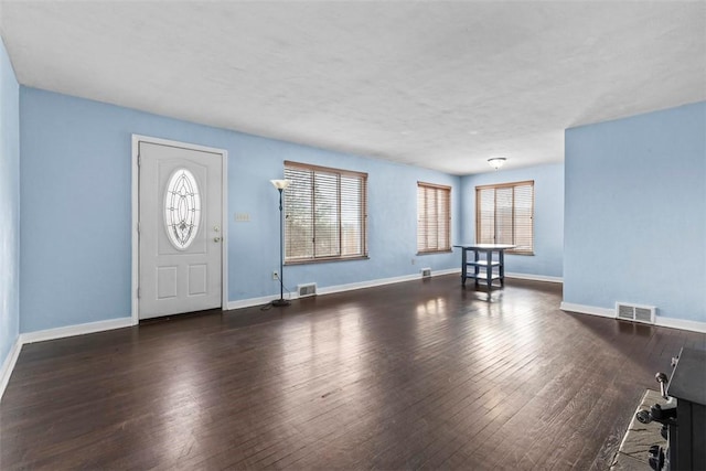 entryway with dark wood-type flooring, visible vents, and baseboards