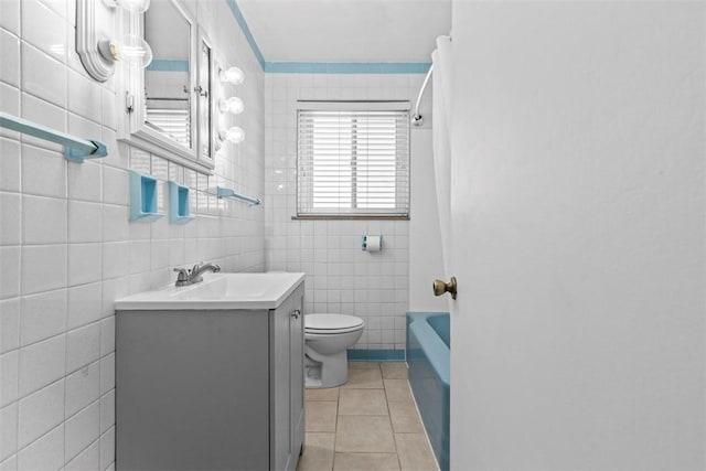 bathroom featuring toilet, vanity, tile patterned flooring, shower / bathtub combination, and tile walls