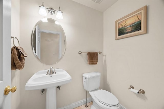 half bath with baseboards, a sink, and toilet