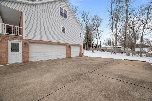 snow covered property with a garage, driveway, and brick siding