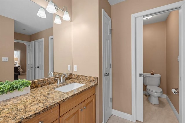 bathroom featuring a closet, toilet, vanity, tile patterned flooring, and baseboards