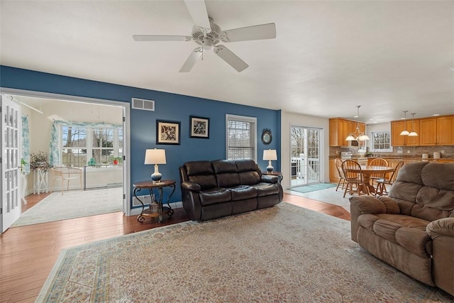 living area with ceiling fan, baseboards, visible vents, and light wood-style floors